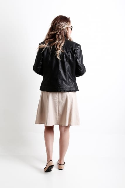 Modelo de costas utilizando uma saia bege com uma jaqueta de couro legítimo da marca javali 