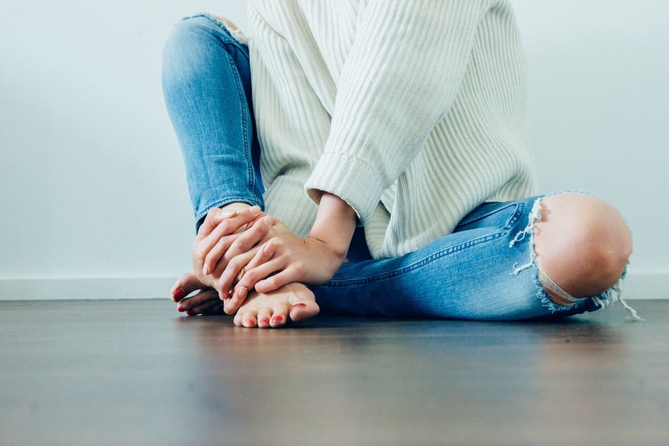 moça de calça jeans rasgada sentada no chão