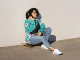 jovem moça usando roupas streetwear senta em cima de um skate