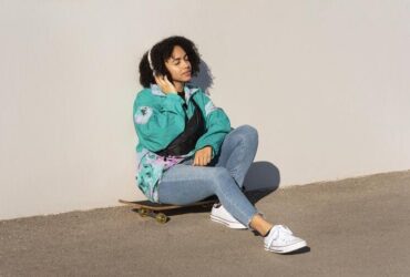 jovem moça usando roupas streetwear senta em cima de um skate