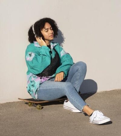 jovem moça usando roupas streetwear senta em cima de um skate