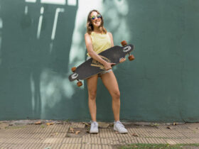 adolescente vestida com camiseta básica amarela, tênis branco e bermuda jeans, segurando um skate
