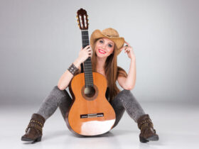 Moça com look sertanejo sentada com violão à frente