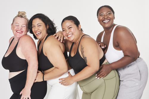 4 mulheres plus size pousando para uma foto