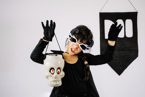 Muça usando um look para halloween composto por bolsa, luvas, e máscara