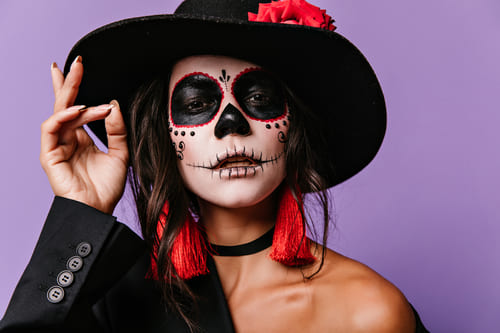 Mulher com maquigem de halloween usando um chapéu preto bem apropriado para ocasião