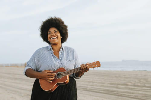 Mulher negra tocando cavaquinho na praia