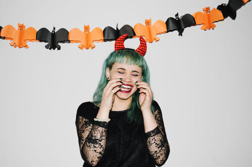 Mulher usando tiara de diabinha rindo em uma decoração para halloween