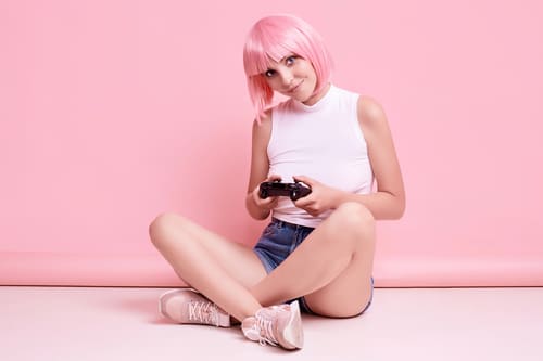 Nulher de cabelo rosa e joystick num estúdio para um ensaio geek 