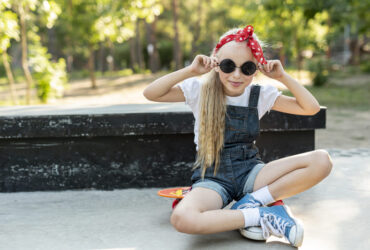Garota usando um look com bandana vermelha, oculos de sol, e tênis allstar jeans