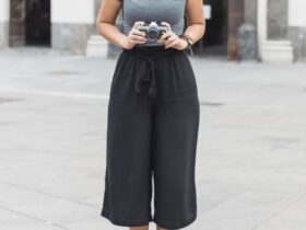 Mulher com camera na mão usando uma calça pantalona