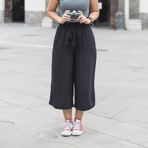 Mulher com camera na mão usando uma calça jogger preta