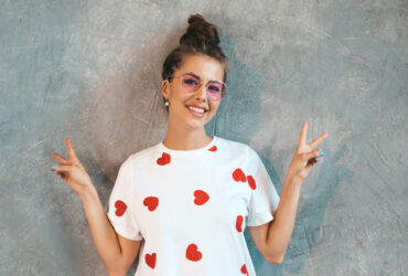 mocinha usando uma blusinha básica branca com detalhes no formato de corações vermelhos