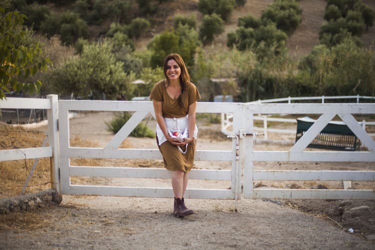 Mulher usando roupas country em frente a porteira