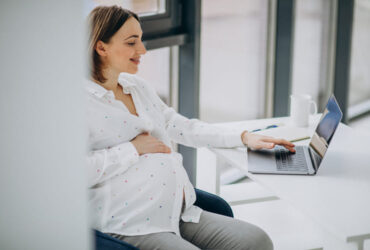 jovem mulher excutiva grávida trabalhando na frente de um notebook