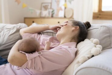 Mulher deitada cochilando e amamentando seu filho