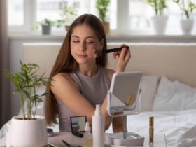 Mulher se maquiando na frete do espelho