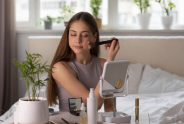 Mulher se maquiando na frete do espelho