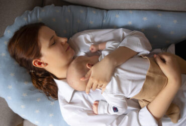 Mulher deitada descansando com o filho no colo