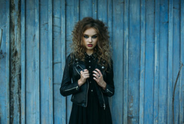 Mulher usando um look totalmente dark, com jaqueta de couro e vestido, ambos pretos