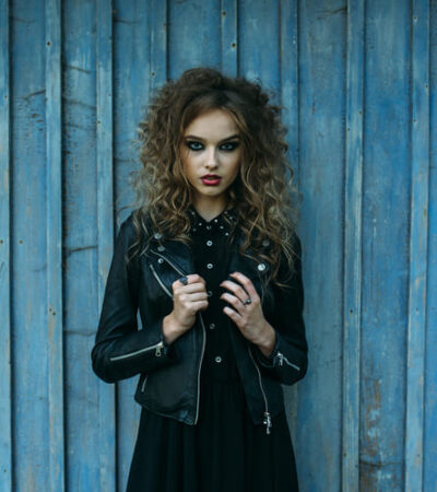 Mulher usando um look totalmente dark, com jaqueta de couro e vestido, ambos pretos