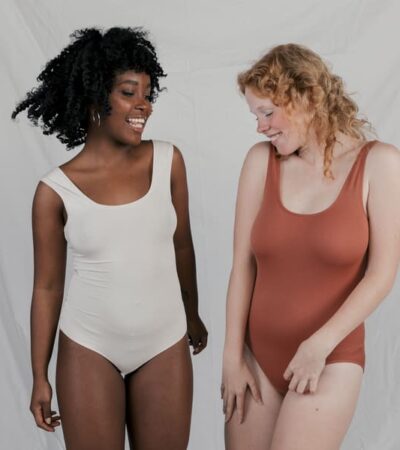 Duas mulheres usando bodies plus size, sendo uma cor nude e outra na marrom.