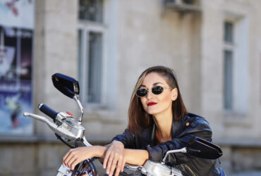 Mulher de roupas de couro preta sentada numa moto