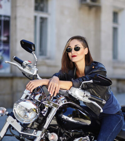 Mulher de roupas de couro preta sentada numa moto