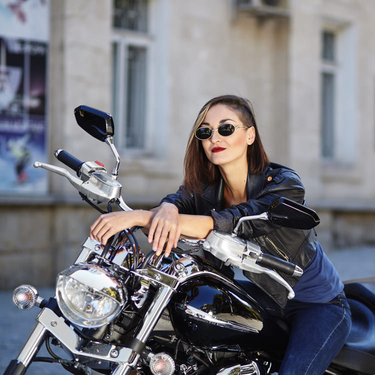 Mulher de roupas de couro preta sentada numa moto