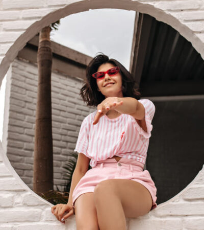 Mulher com conjunto rosa claro sentada para ensaio de fotos