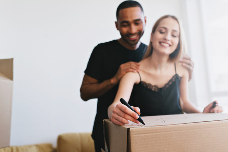 Casal organizando caixas de mudança e pensando no novo lar