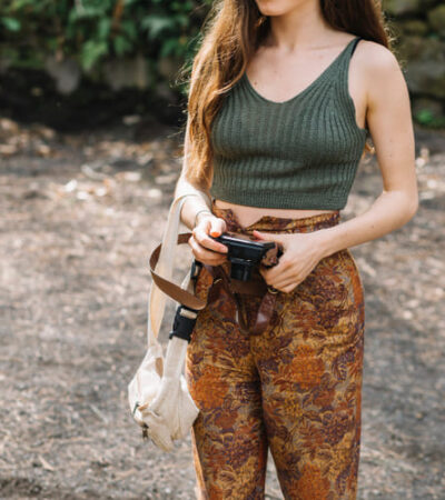Mulher com uma máquina fotografica-na-mao-usando-calca-estampa-militar-e-um top-verde