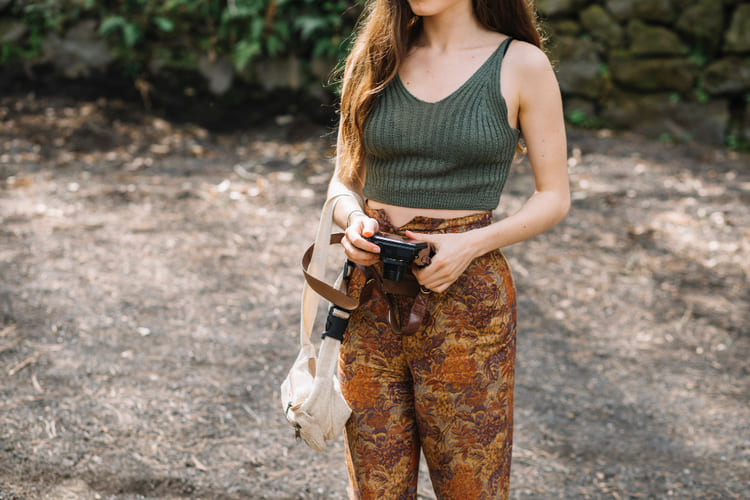 Mulher com uma máquina fotografica-na-mao-usando-calca-estampa-militar-e-um top-verde