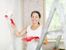 Mulher com pincel na mão pintando uma parede de sua casa