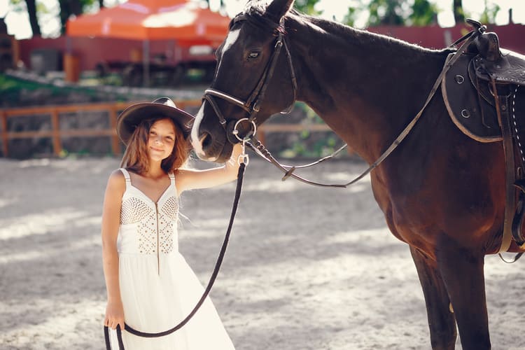 Garota com vestido branco cowntry segurando um cavalho