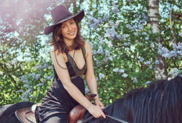 Mulher usando vestido country preto andando de cavalo
